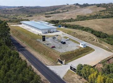 Vista aérea panorâmica da planta industrial do laticínio à venda em Barbacena/MG, destacando o terreno de 60.000 m² e a facilidade de acesso logístico. · Laticínio à Venda em Barbacena MG | Indústria com SIF