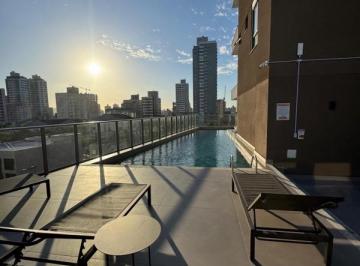 Piscina do Brooklyn 365 com deck e espreguiçadeiras, no fim de tarde · Brooklyn 365: 47 m² com suíte e 2 vagas, pronto no Centro de Itajaí
