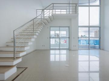 Living com pé-direito duplo, escada para o mezanino e porta de vidro para a sacada · Apartamento com 2 suítes em Balneário Camboriú - Vermont