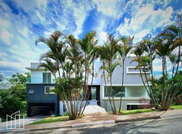 Fachada da casa zero km com palmeiras, no condomínio Chácara dos Lagos. · Casa zero km em condomínio, Chácara dos Lagos, 4 suítes, moderna, piscina com bo