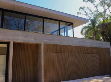 Fachada com portões de madeira e grandes janelas · Casa de 407 m² com 3 suítes e 4 vagas no AYA Casas, Praia do Estaleiro